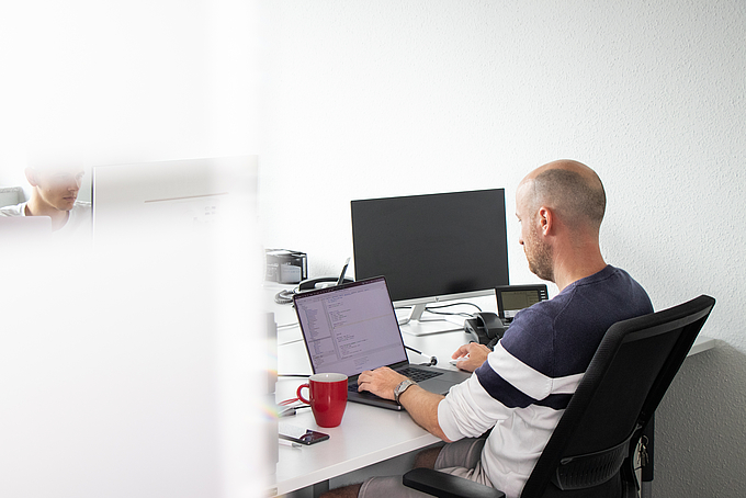 Mitarbeiter arbeitet am Laptop an der technischen Optimierung digitaler Inhalte für mehr Sichtbarkeit in Suchmaschinen und KI-Systemen.