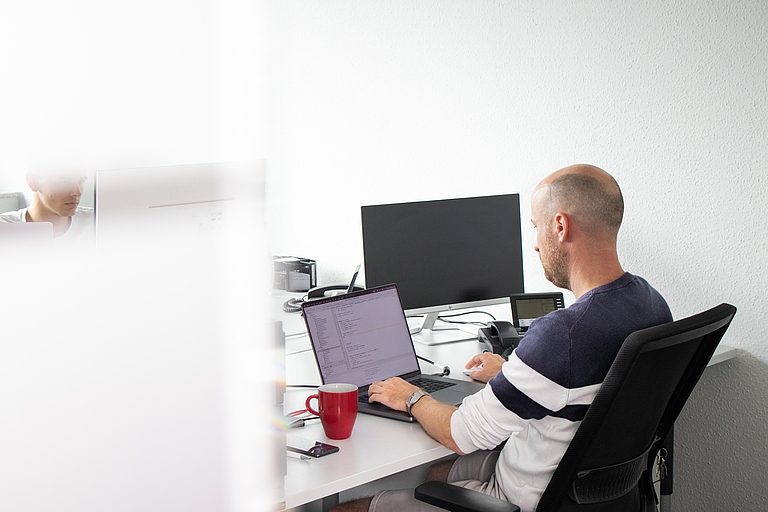 Mitarbeiter arbeitet am Laptop an der technischen Optimierung digitaler Inhalte für mehr Sichtbarkeit in Suchmaschinen und KI-Systemen.