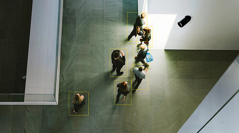 Eine Kamera erfasst Menschen und kennzeichnet diese mit einem gelben Rahmen