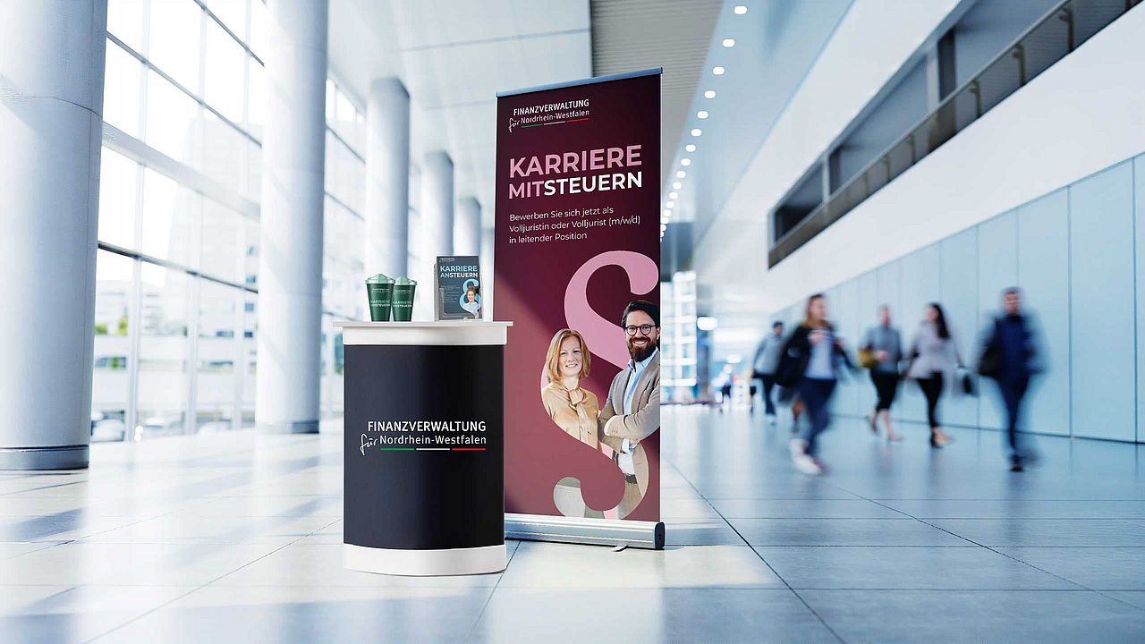 Messestand der Finanzverwaltung NRW mit Banner "Karriere mitsteuern" und Personen im Hintergrund