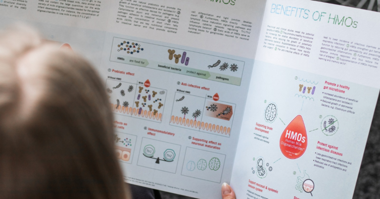 Person betrachtet eine aufgeklappte, gedruckte Informationsbroschüre mit wissenschaftlichen Grafiken, Diagrammen und Texten.
