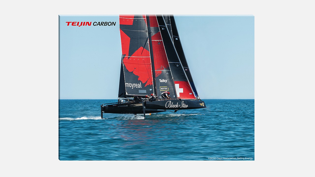 Ein Black Star GC32 Segelkatamaran mit rotem und schwarzem Segel in voller Fahrt auf dem Wasser, mit Teijin Carbon Logo.