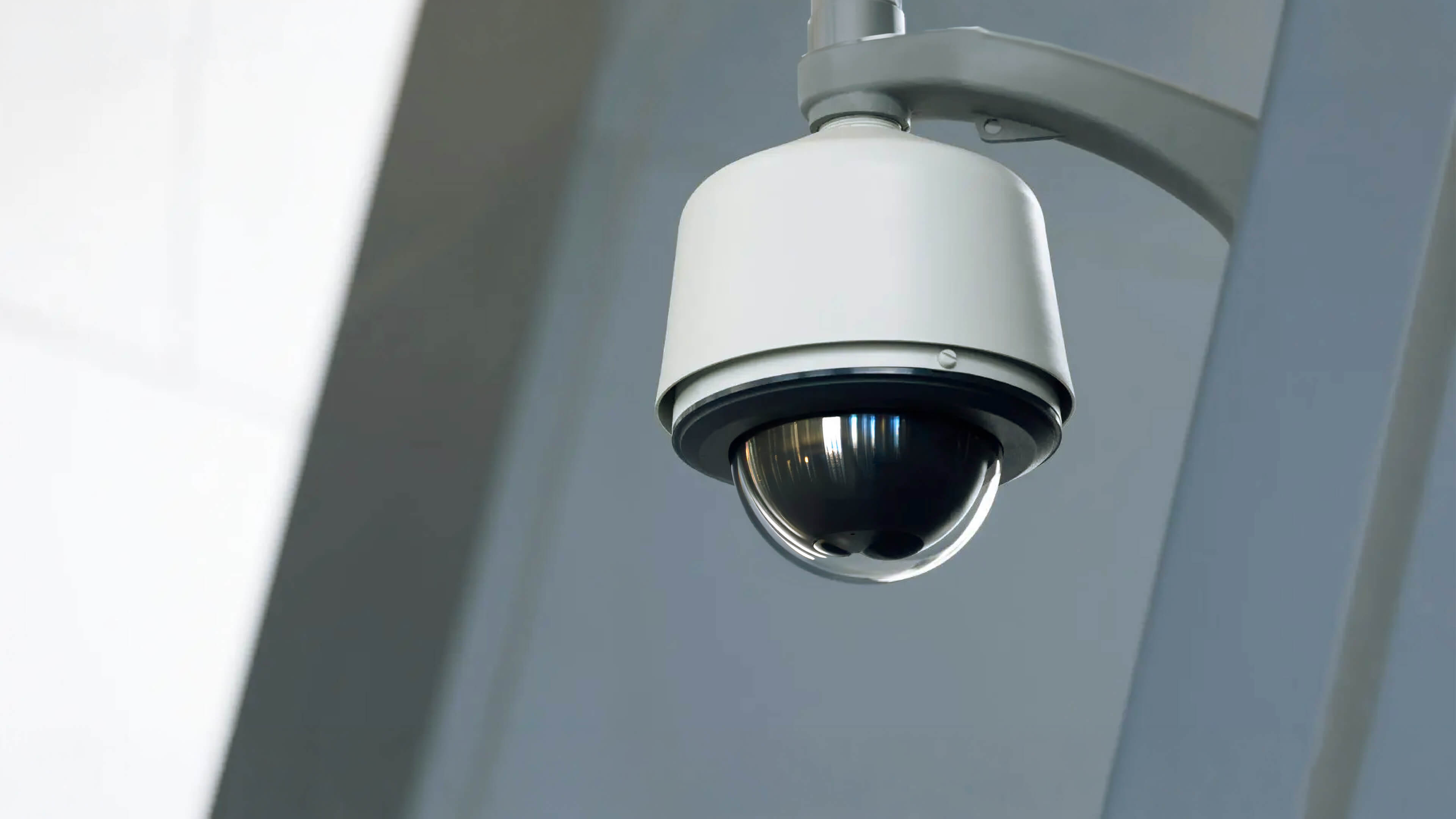 Weiße PTZ-Dome-Sicherheitskamera an einer Außenwand zur Videoüberwachung von Gebäuden.